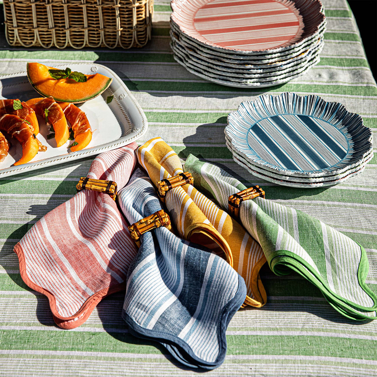 Overhead view of Cabana Stripe Napkin Assorted, Set of 4 in Multi with colorful striped linen and scalloped trim on a table