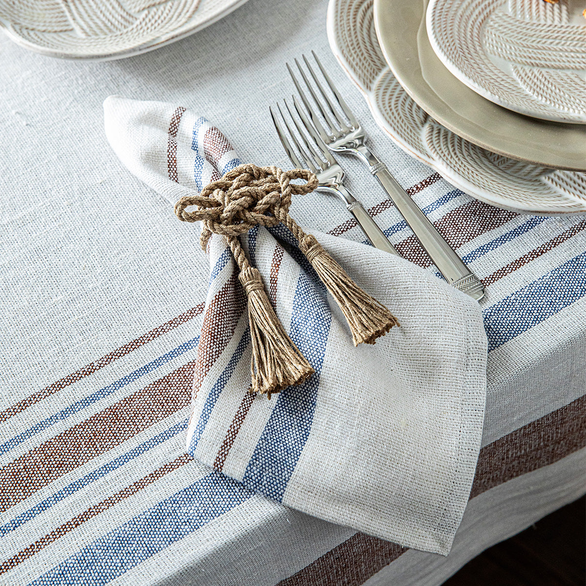 Angled view of Danish Stripe Napkin in Taupe, Set of 4 showcasing woven linen stripes with a table setting
