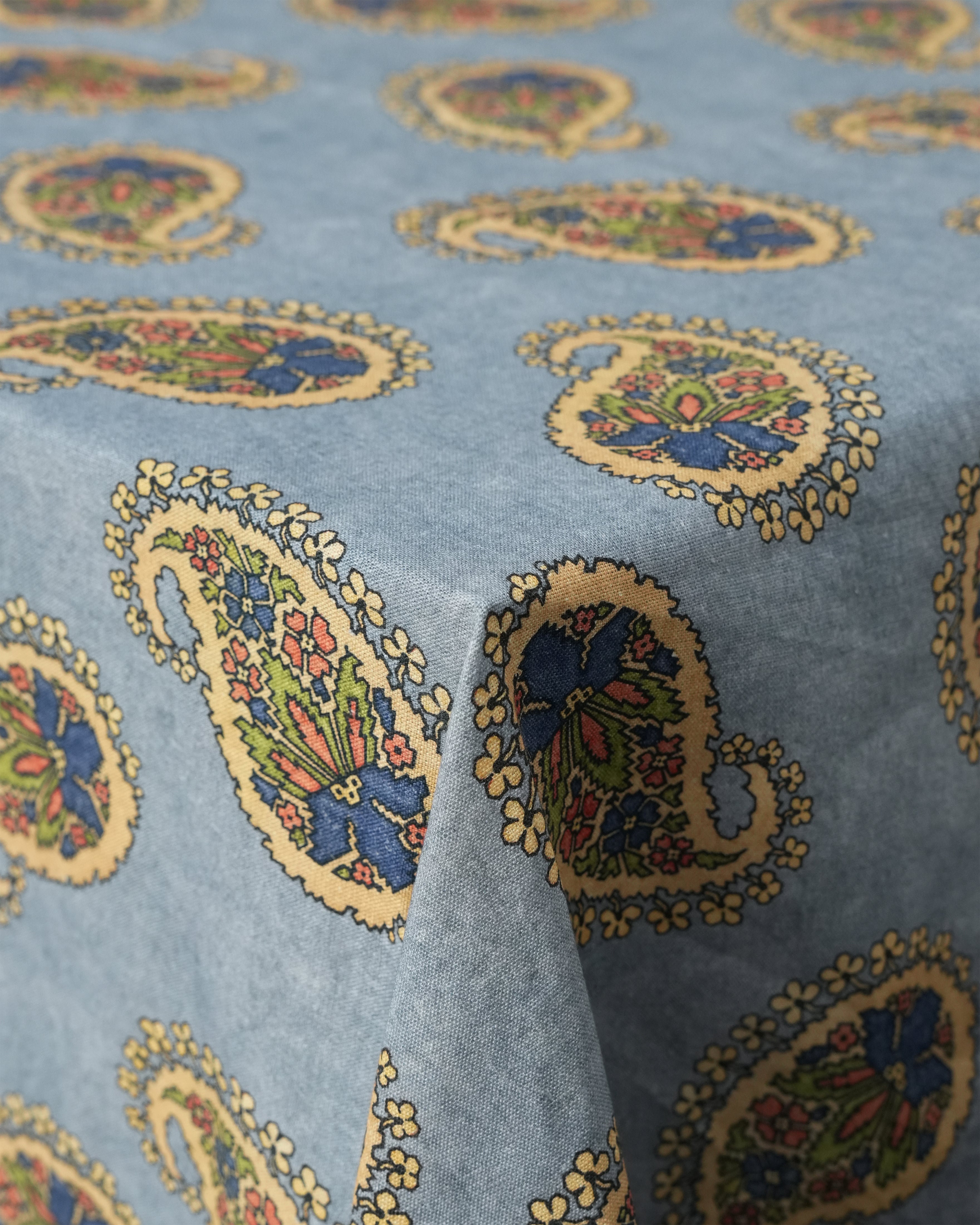 Close-up of Square Babe Tablecloth showing paisley print and linen texture on light blue background