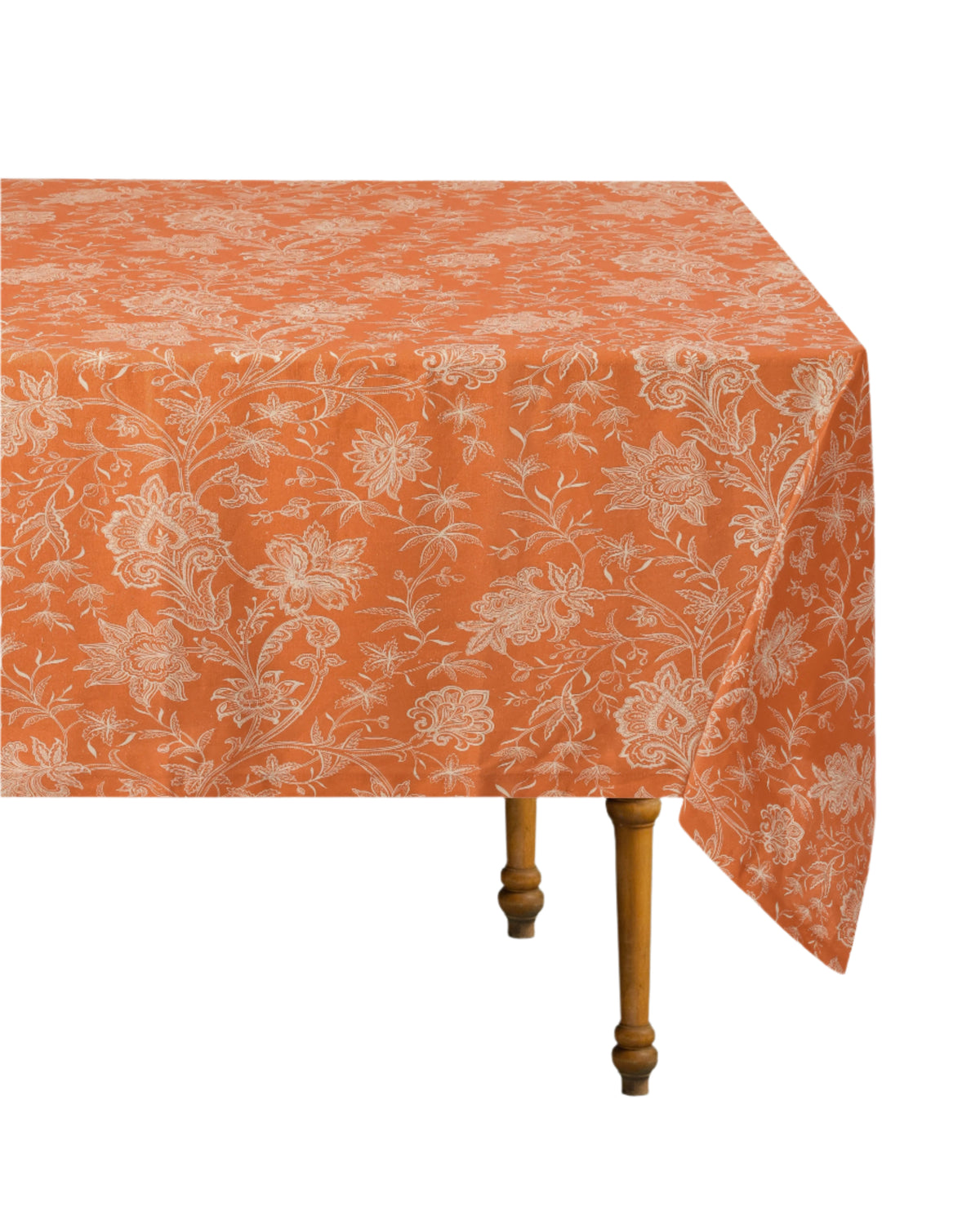 Angled view of DESTREE x Cabana tablecloth in orange showing white floral print on linen draped over a wooden table against a white background