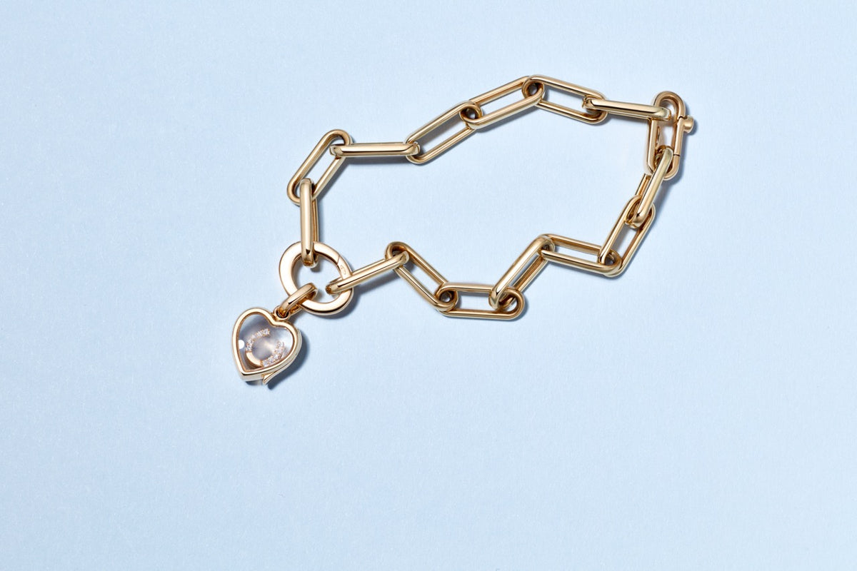 Top view of Single Heart Locket Link Bracelet showcasing oval links and heart locket in 14K solid gold on a light blue background