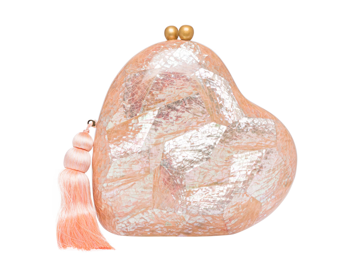 Front of Love Clutch heart-shaped pink abalone shell minaudiere with iridescent inlay, gold clasp and tassel on white