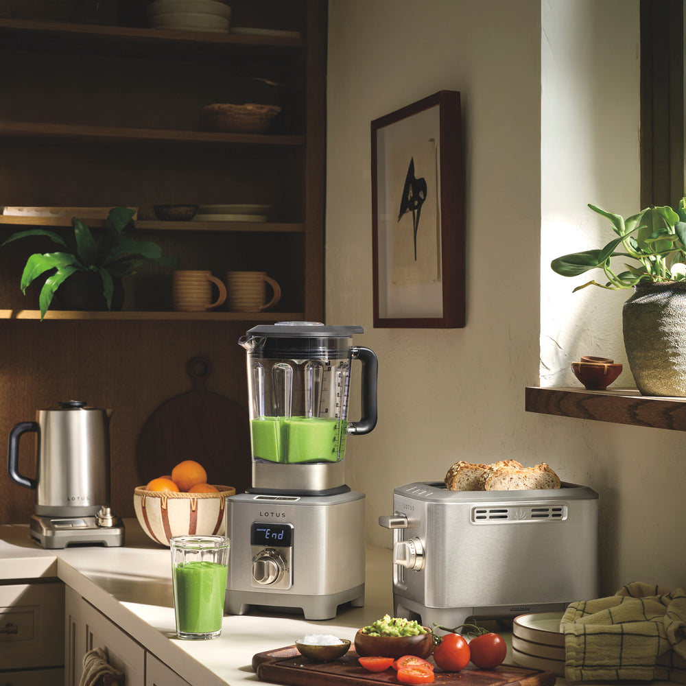 Power Spin Infinite Speed Control blender with stainless steel base and clear pitcher of green smoothie on a kitchen counter