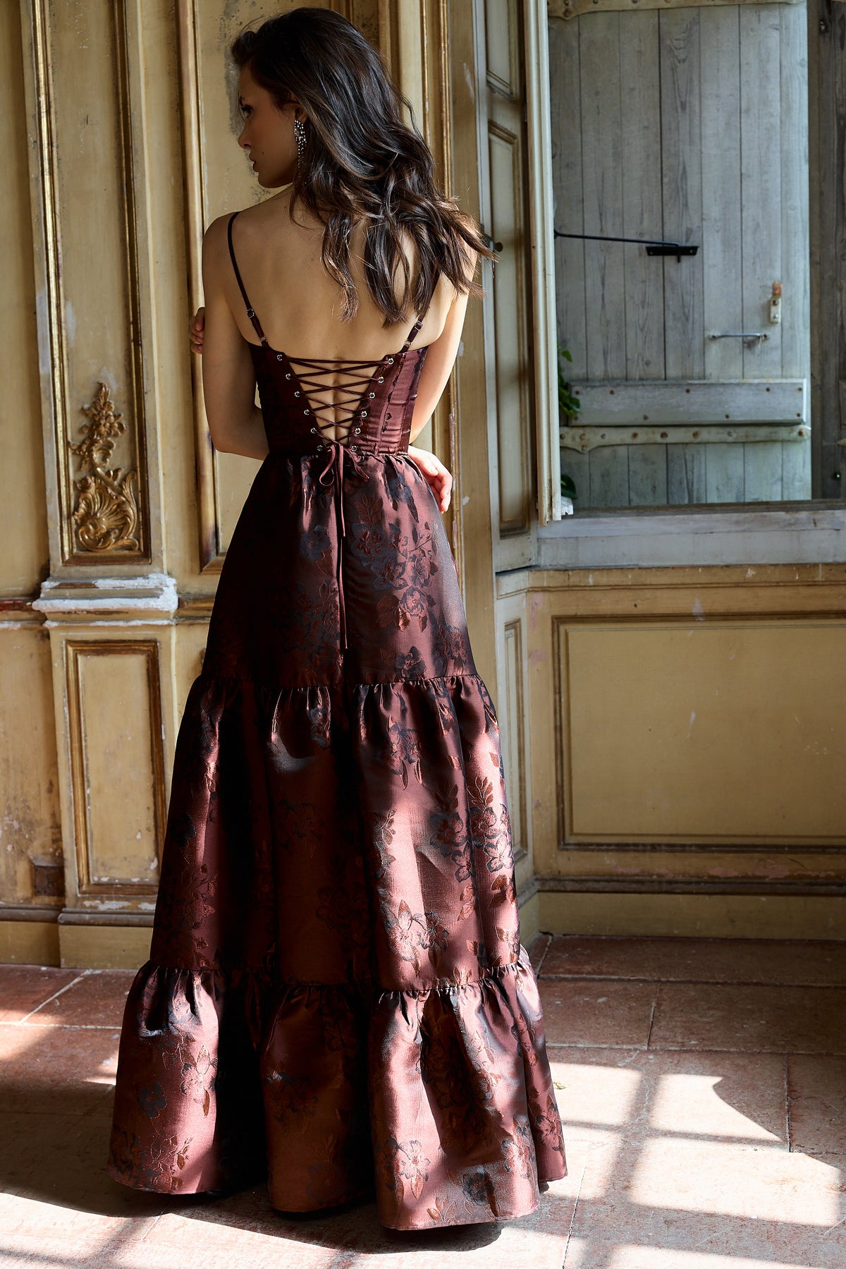 Back view of The Lucetta Dress in Andorra Baroque Floral showcasing corset lacing and tiered skirt in a vintage room