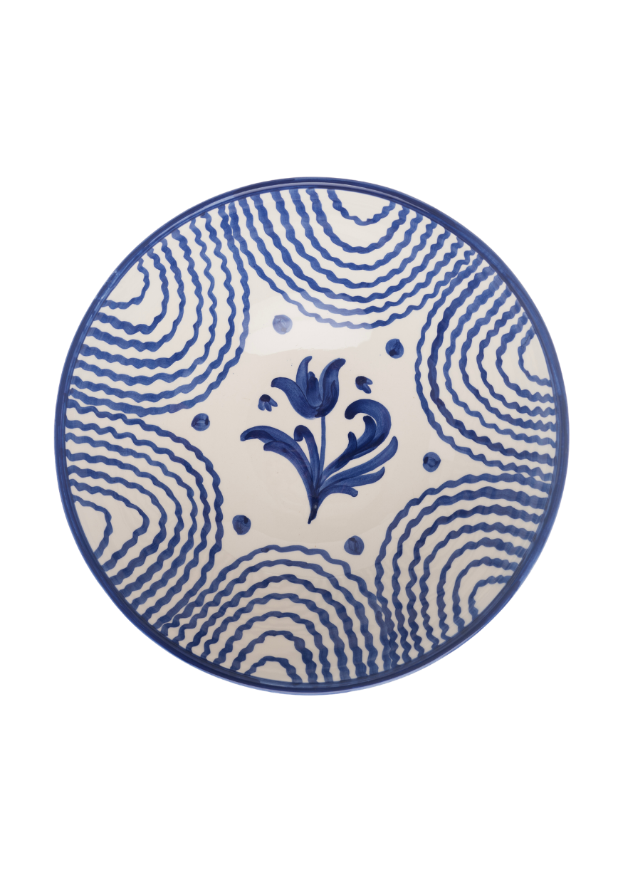 Top-down view of Flor very large blue serving bowl showcasing hand-painted central floral motif and wavy blue concentric stripes on white background