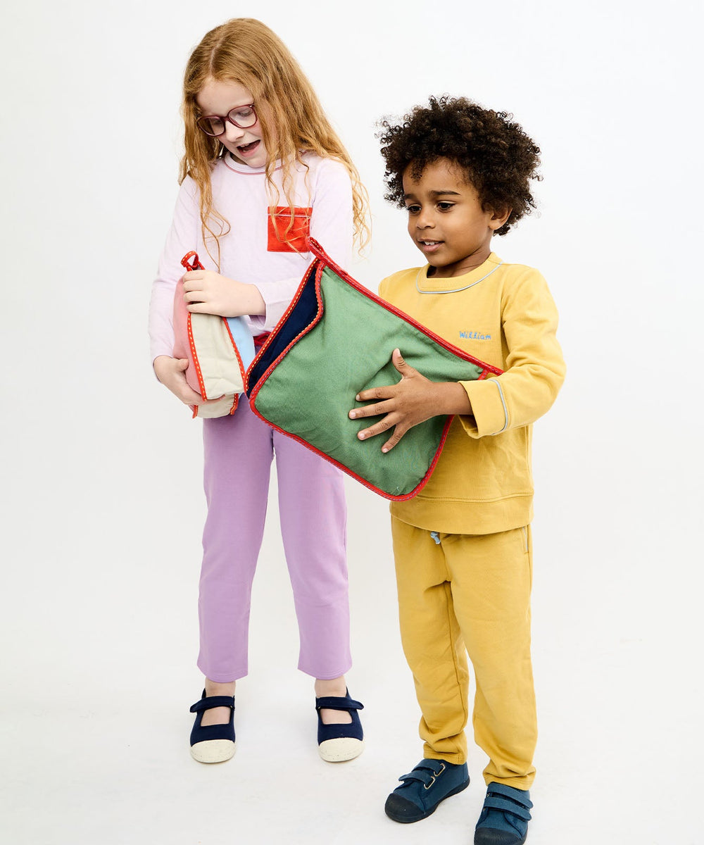 Two children open and examine large zip bags in Cool Color Block in a white studio setting