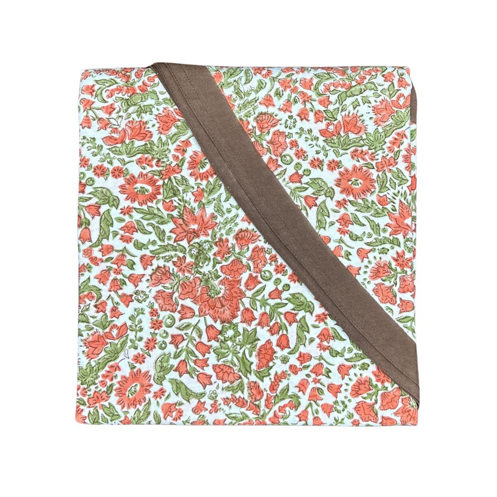 A hand block printed tablecloth, featuring a floral pumpkin and  sage green floral pattern on a white background, finished with a brown band and Greek key border at the bottom, 90 inch round tablecloth, Thanksgiving tablecloth