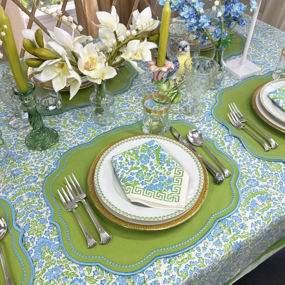 Elegant table setting with floral centerpieces, green and blue tablecloth, and silverware. hand block printed tablecloth, luxury embroidered green placemats with blue embroidery.