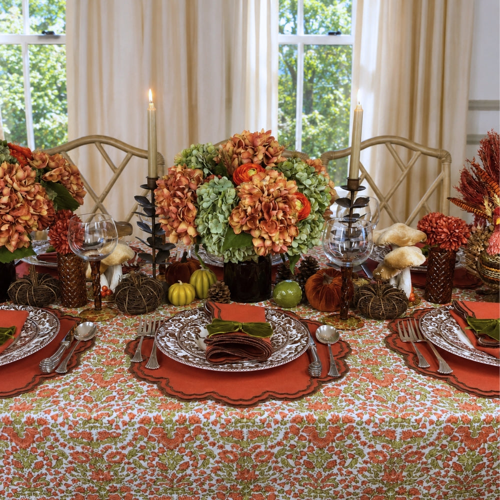 A hand block printed tablecloth, featuring a floral pumpkin and sage green floral pattern on a white background, finished with a brown band and Greek key border at the bottom, Thanksgiving tablecloth, luxury table linens