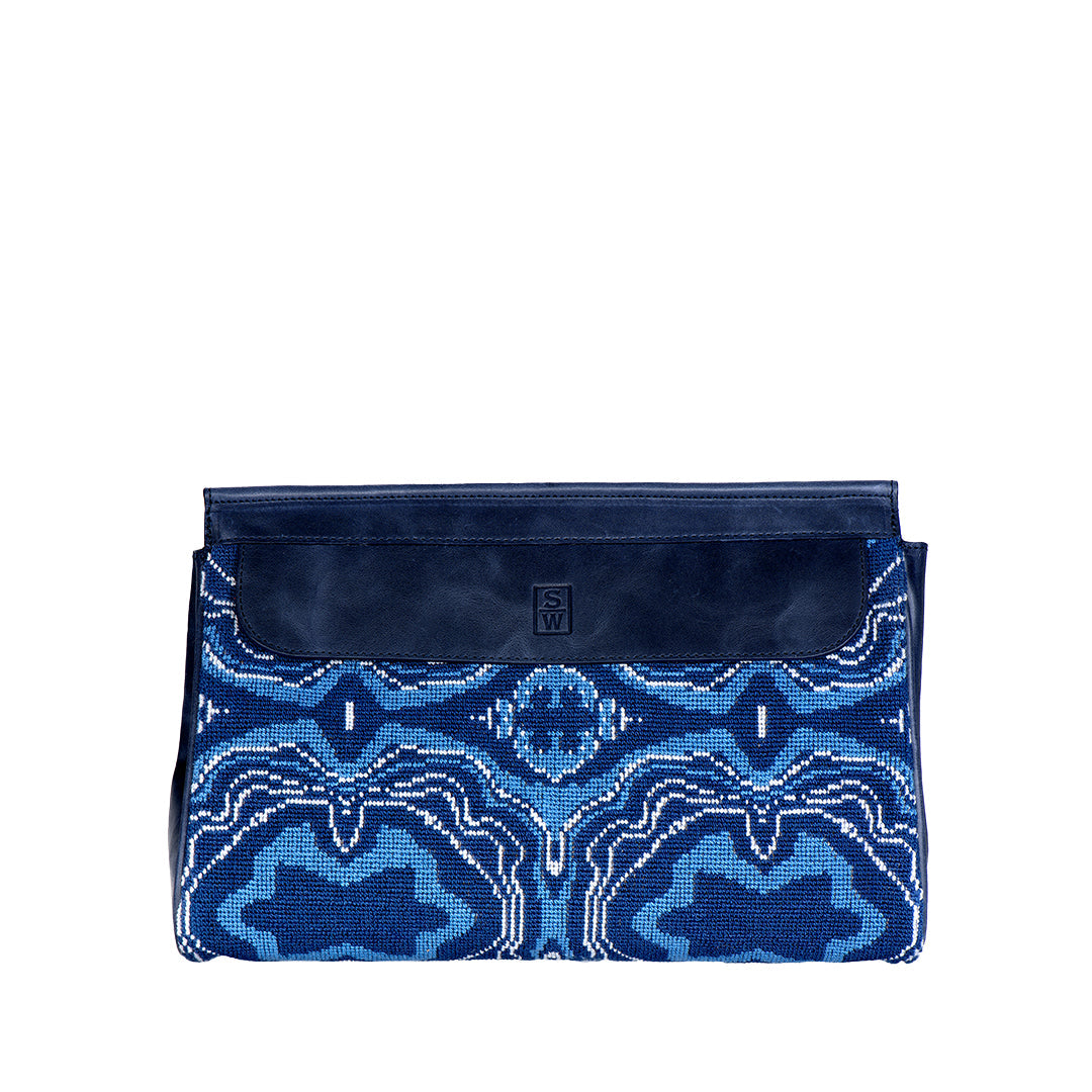 Front view of Lazurite Traveler pouch showcasing blue and white geometric needlepoint and navy leather flap on white background