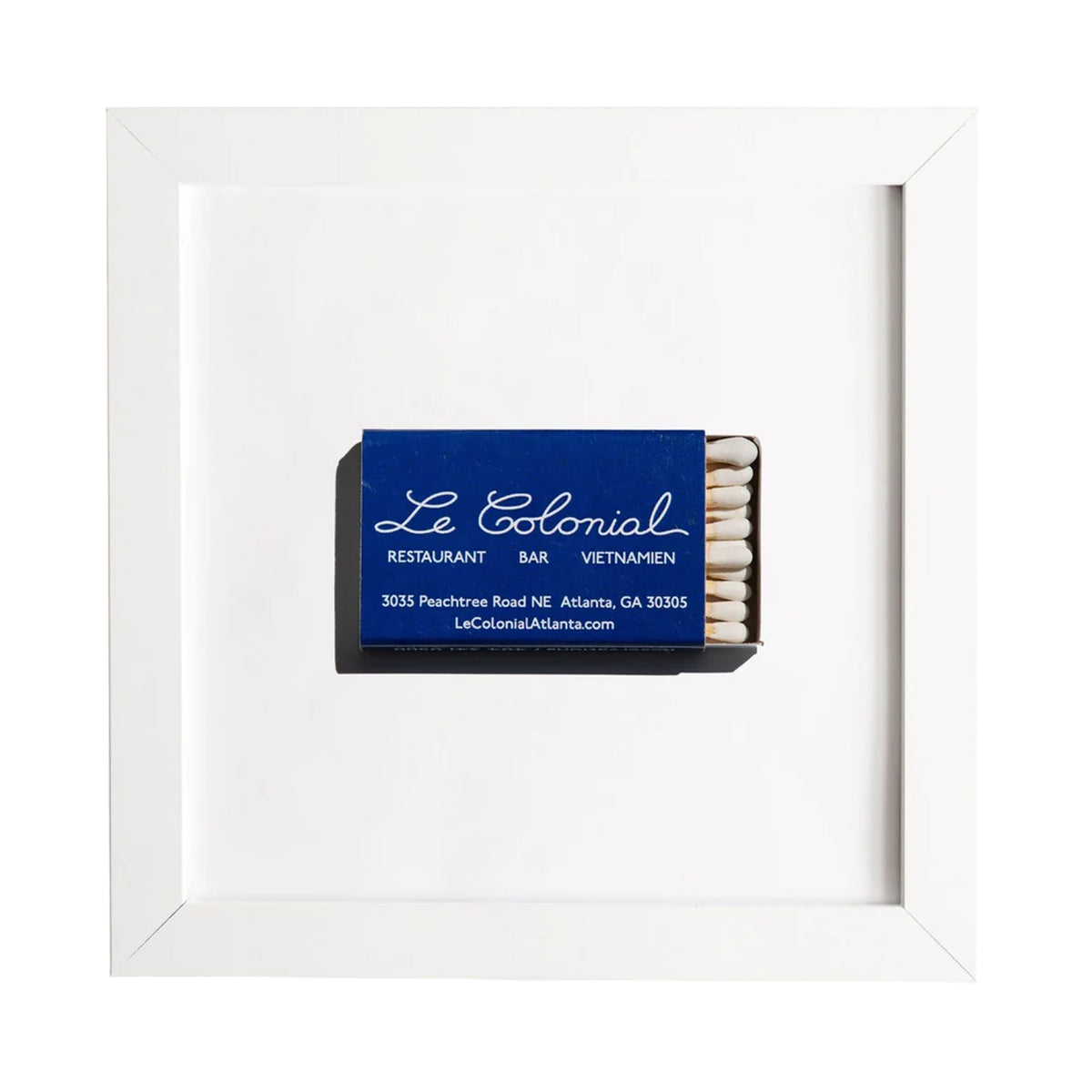Front view of framed Le Colonial matchbook print showcasing a blue matchbox centered in a white frame on a white background