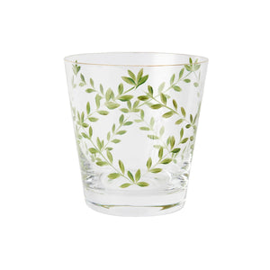 A product photograph of a clear glass tumbler with a subtle tapered shape and a gold rim, shown against a light gray background. The front of the glass is delicately hand-painted with a botanical design featuring slender, arching green branches and delicate leaves arranged in an elegant, symmetrical wreath formation.