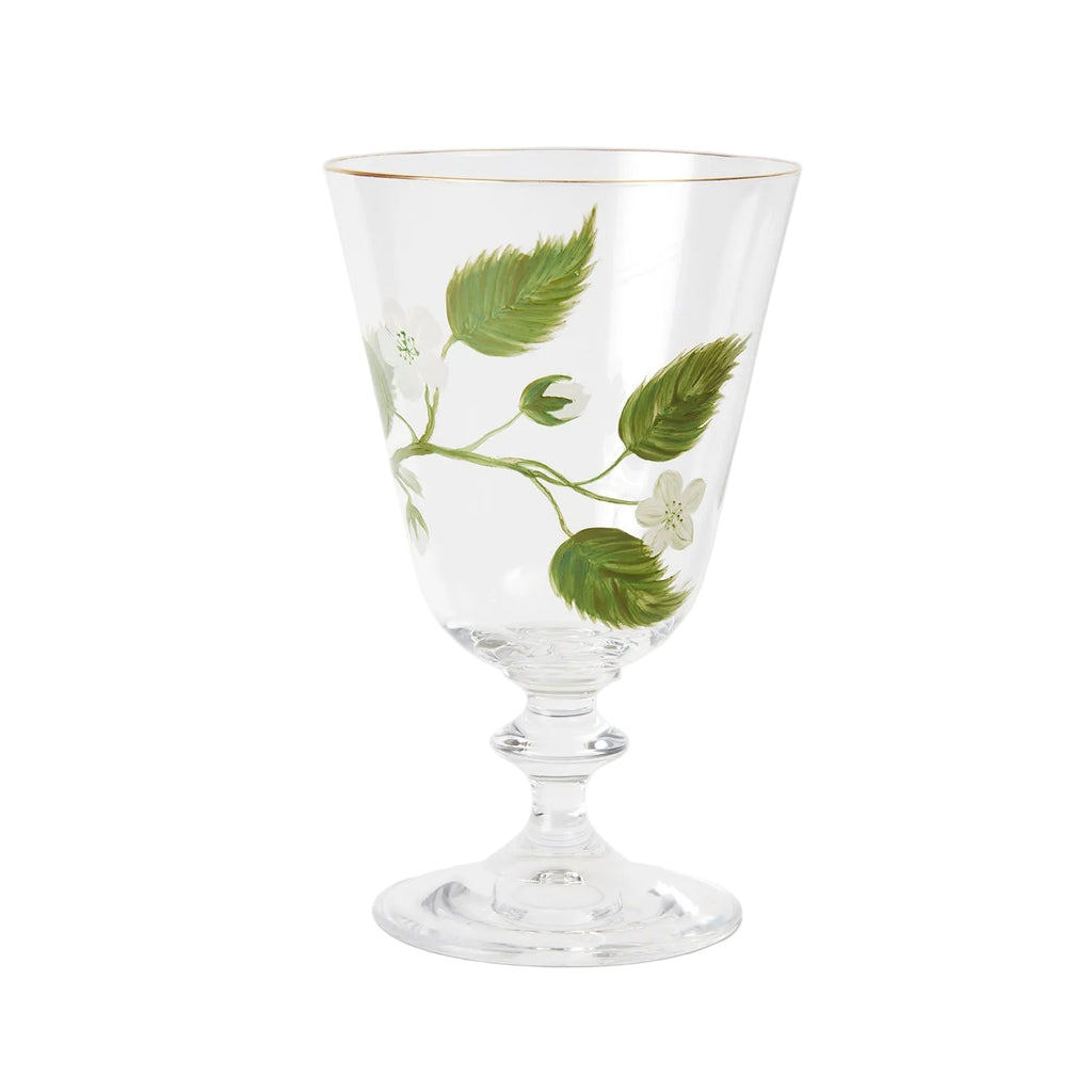 A product photograph of an elegant, clear glass wine or water glass with a footed stem and a fine gold rim, set against a clean, light gray background. The front of the glass is delicately hand-painted with a botanical design featuring a slender green branch with leaves and small white blossoms.
