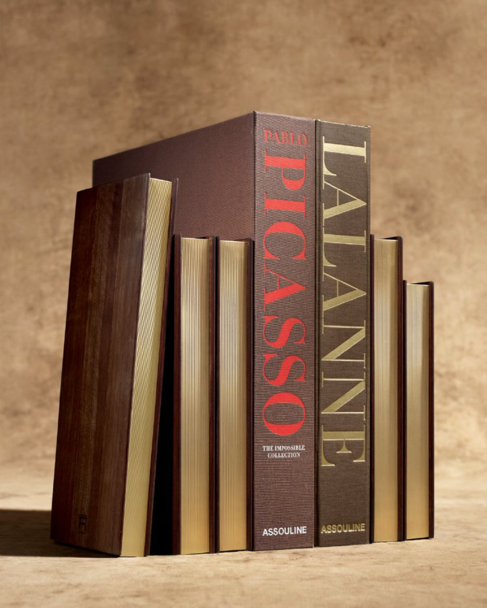Front view of Assouline Library Bookends set of 2 in walnut with brushed-brass pages styled like stacked books on beige background