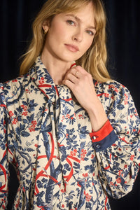 The Lila Dress is a mini with a tie neckline, long sleeves with button cuffs and a color block hem. 