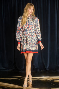 The Lila Dress is a mini with a tie neckline, long sleeves with button cuffs and a color block hem. 