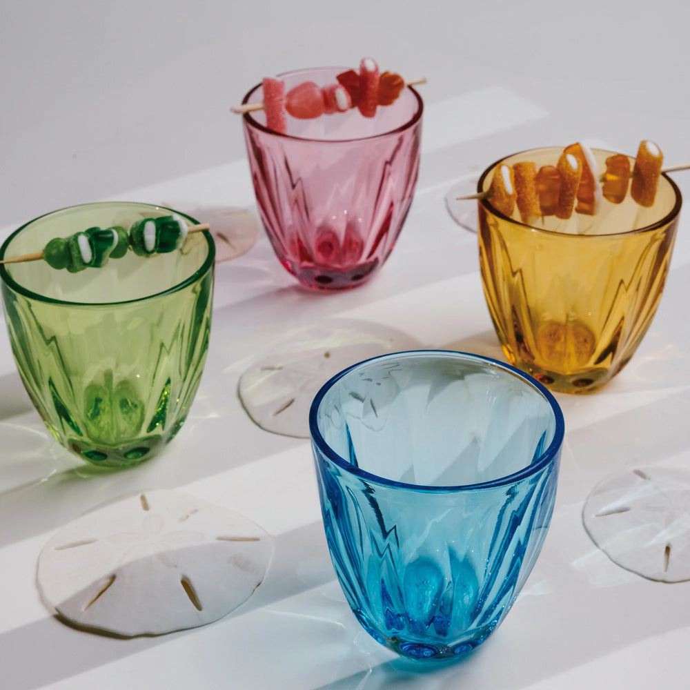 Three-quarter view of Lily tumblers showcasing fluted glass pattern in assorted colors on a white surface, some topped with candy skewers
