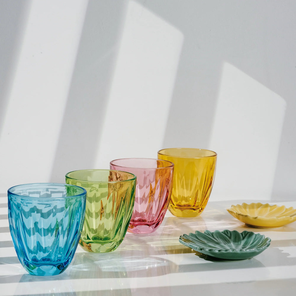 Front view of Lily tumblers showing faceted colored glass in blue, green, pink, and yellow on a sunlit white surface