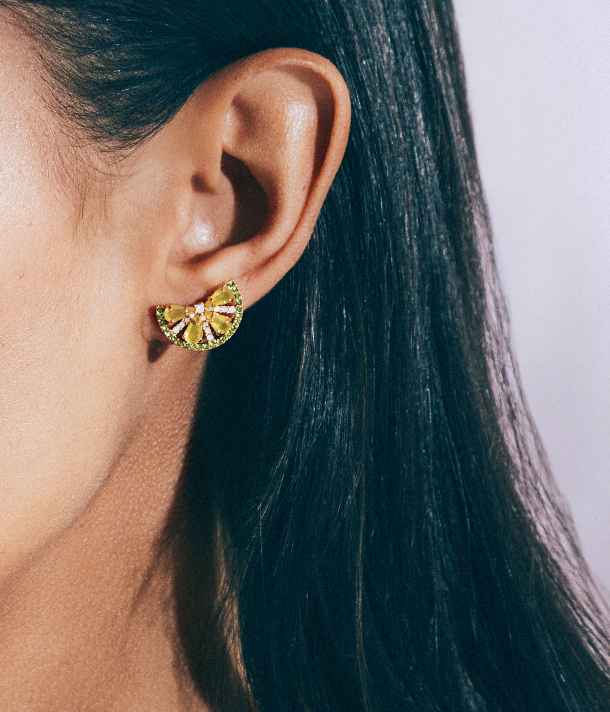 Close-up of ear wearing Lime Slice stud earring showcasing layered lime-green faceted glass stones and shiny gold finish on model