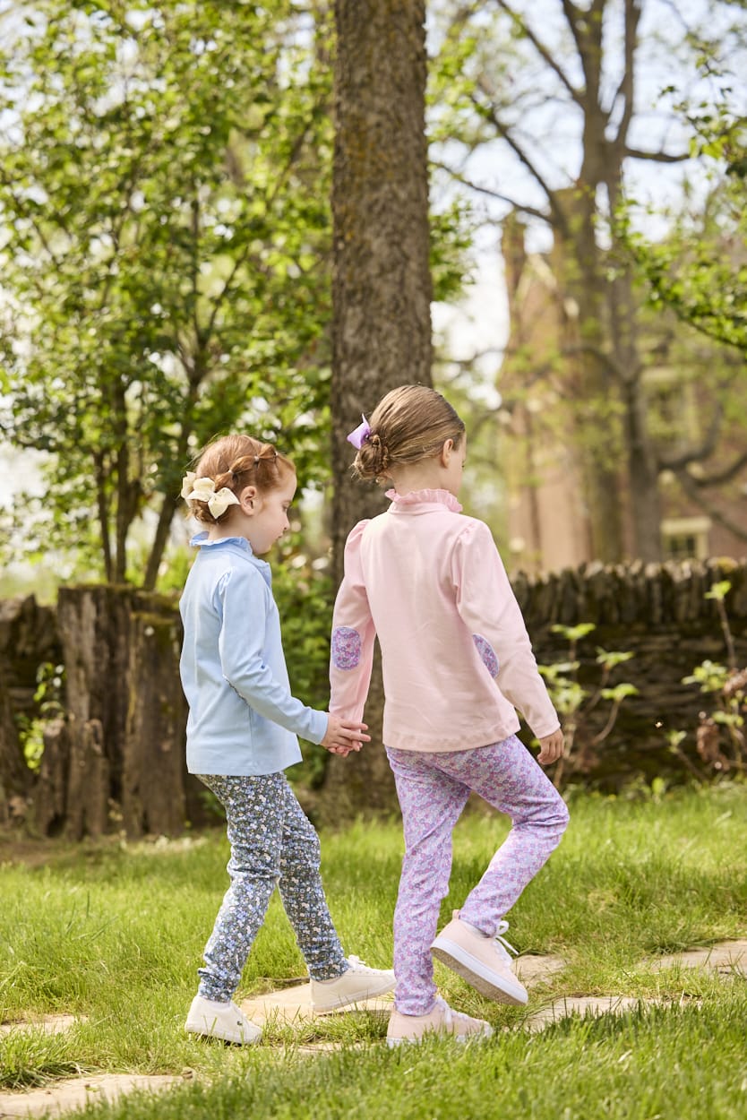 Little English traditional children's clothing.  Long sleeve Hastings polo in light pink with ruffle collar and purple floral detailing. Paired with Purple floral leggings for little girls.  Light blue Hastings polo with green floral detail paired with green floral leggings.