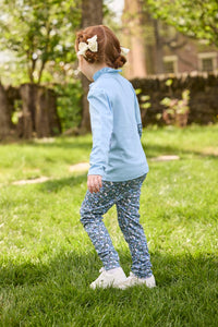 Little English traditional children's clothing.  Long sleeve Hastings polo in light blue with ruffle collar and green floral detailing. Paired with green floral leggings for little girls.  