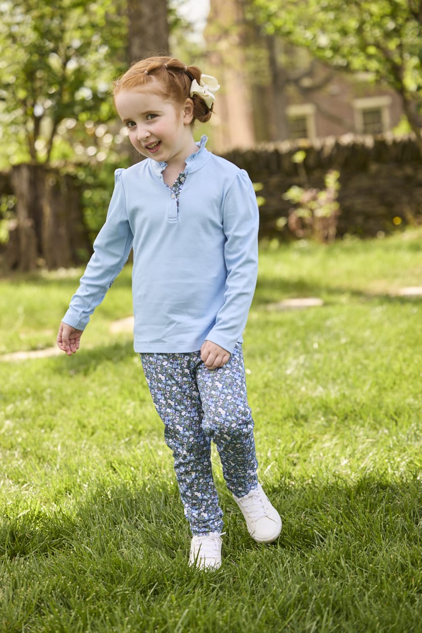 Little English traditional children's clothing.  Long sleeve Hastings polo in light blue with ruffle collar and green floral detailing. Paired with green floral leggings for little girls.  