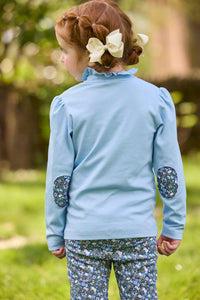 Little English traditional children's clothing.  Long sleeve Hastings polo in light blue with ruffle collar and green floral detailing. Paired with green floral leggings for little girls.  