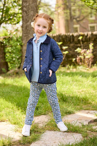 Little English traditional children's clothing.  Long sleeve Hastings polo in light blue with ruffle collar and green floral detailing. Paired with green floral leggings for little girls with navy quilted jacket layered over