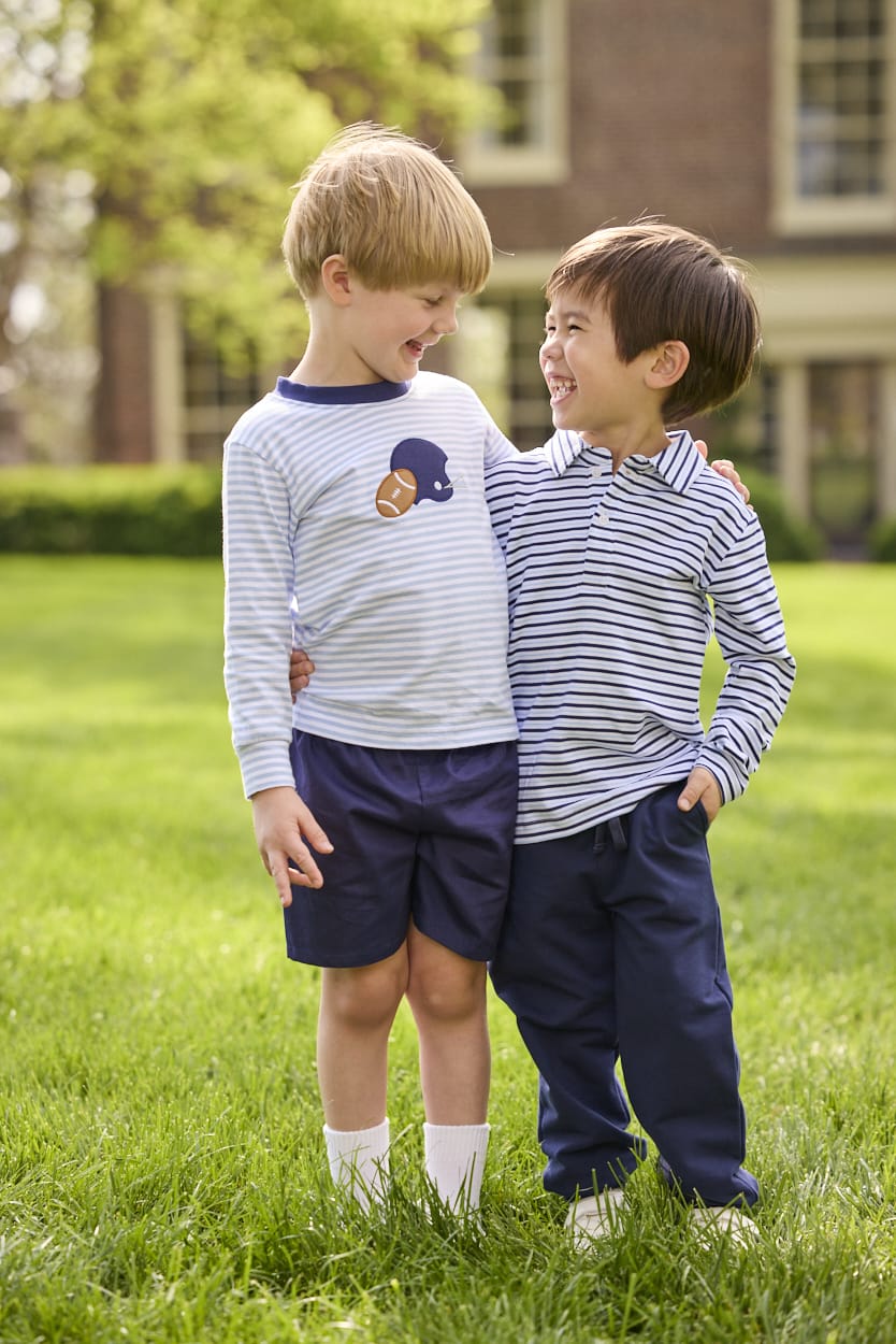 Little English traditional children's clothing.  Light blue and navy Winslow Stripe long sleeve polo shirt paired with navy essential jogger.  Light blue stripe long sleeve applique t-shirt with football and helmet applique paired with navy twill basic shorts.