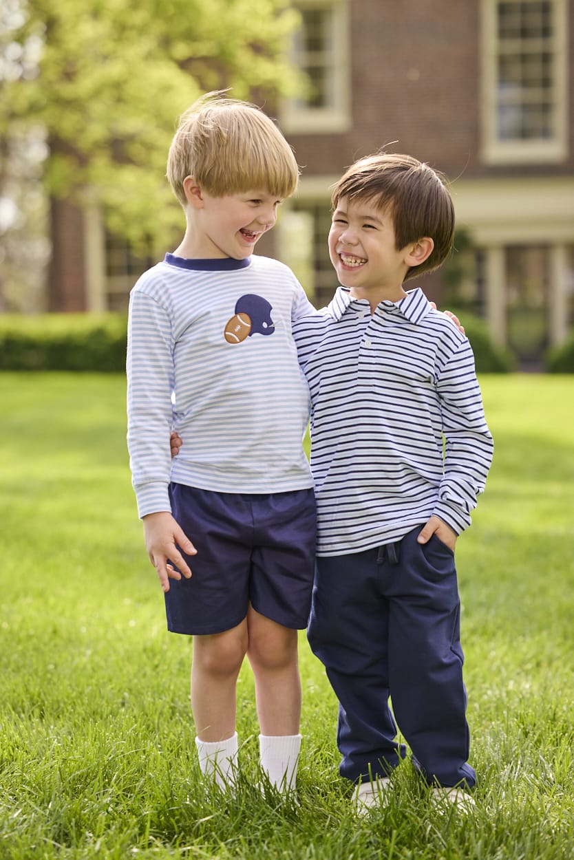 Little English traditional children's clothing.  Light blue and navy Winslow Stripe long sleeve polo shirt paired with navy essential jogger.  Light blue stripe long sleeve applique t-shirt with football and helmet applique paired with navy twill basic shorts.