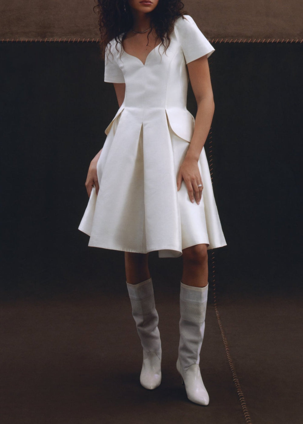Front view of Adeline Dress showcasing its fitted waist, dip neckline, and flared skirt against a dark studio background
