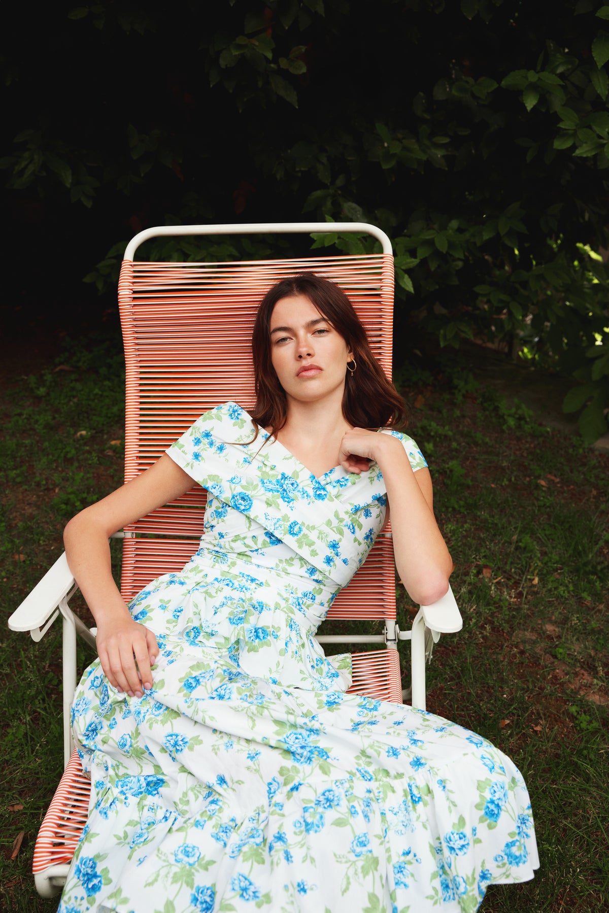Front view of Lily Top in Green showcasing its peplum silhouette and deep V-neck with a garden background