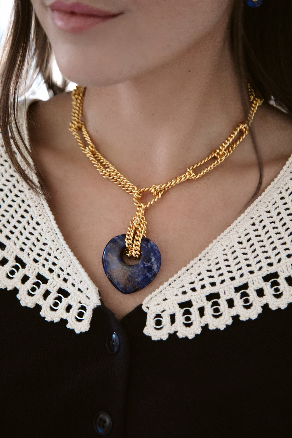 Close-up of Love Link Necklace with blue sodalite heart pendant on 24K antique gold plated chain worn on a model