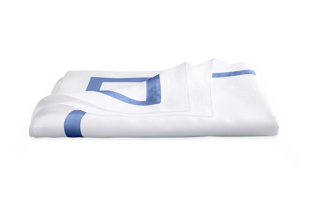 Folded Lowell tablecloth showing azure geometric border on white fabric with black background