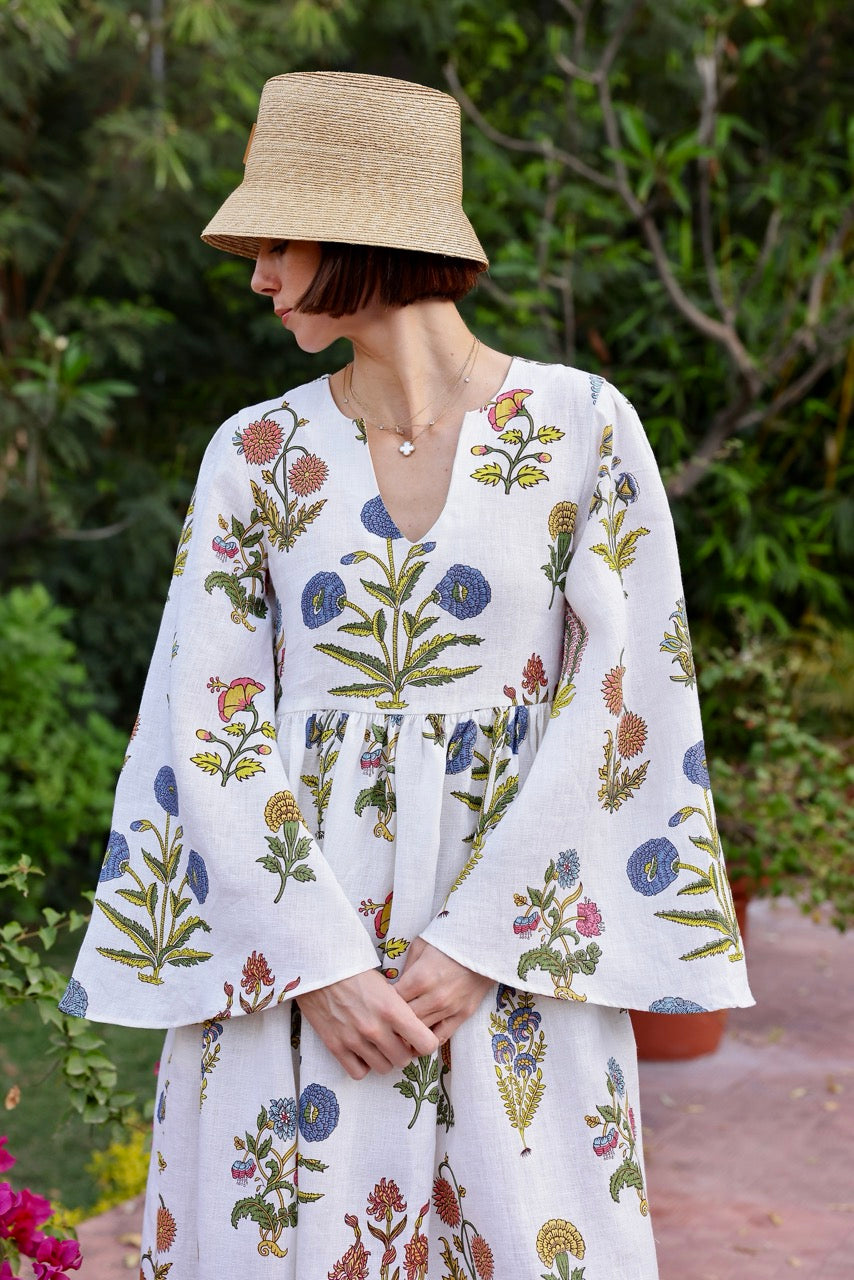 Three-quarter front view of Lugano Maxi Dress in botanical multicolor floral print showcasing V-neck, gathered waist, and bell sleeves in a garden setting