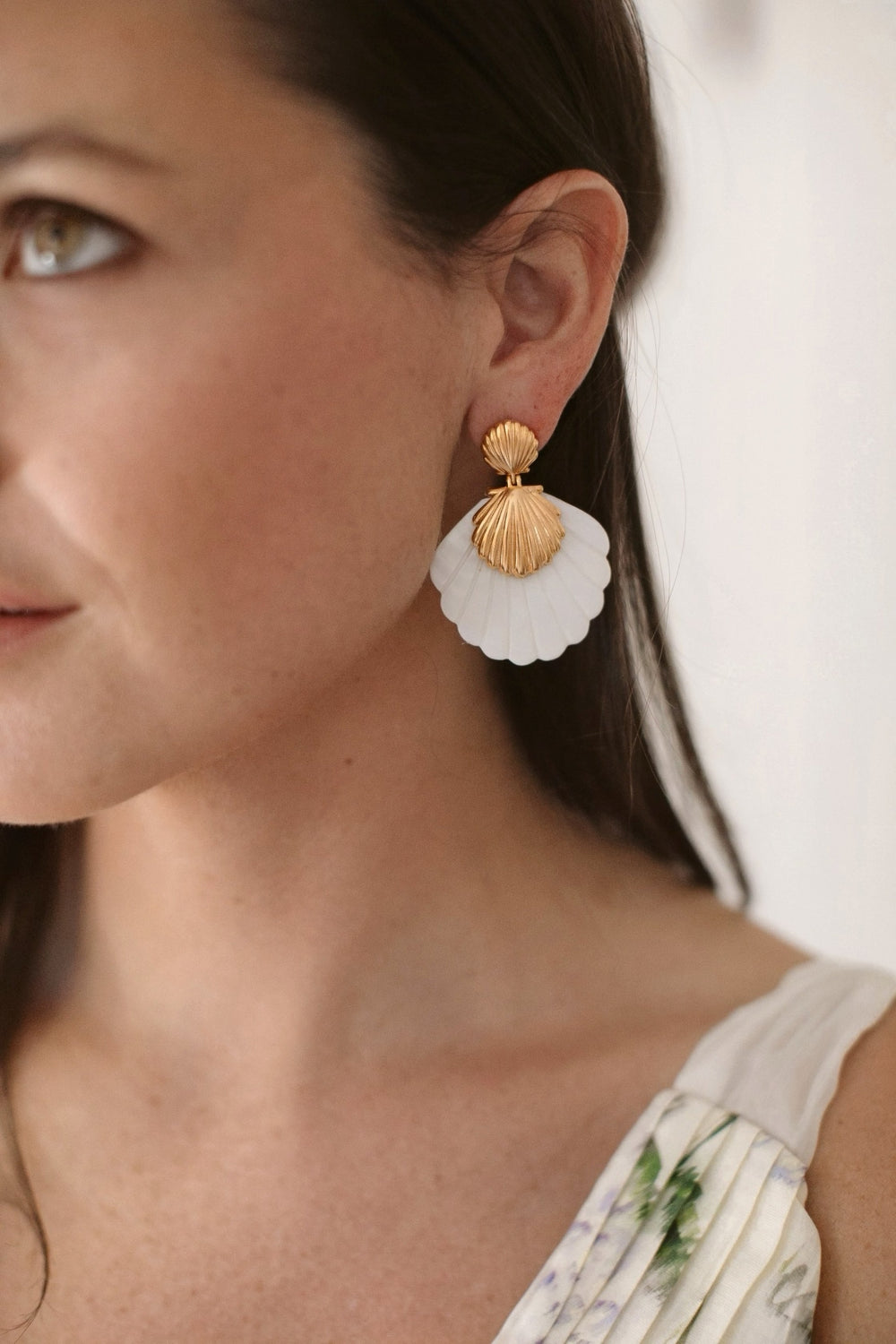 Close-up side view of Lula Earrings showing gold scallop shell studs and white mother-of-pearl fan drops on a model
