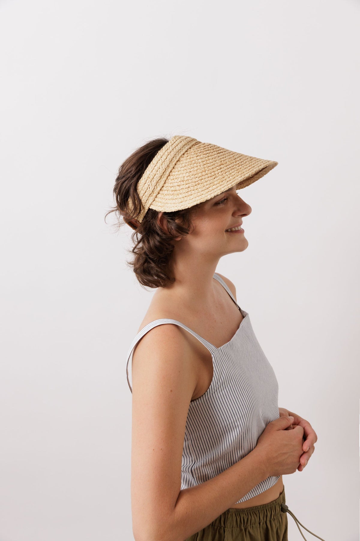 Side view of Marquee Visor Hat in Natural showcasing its wide raffia peak on a model against a white background