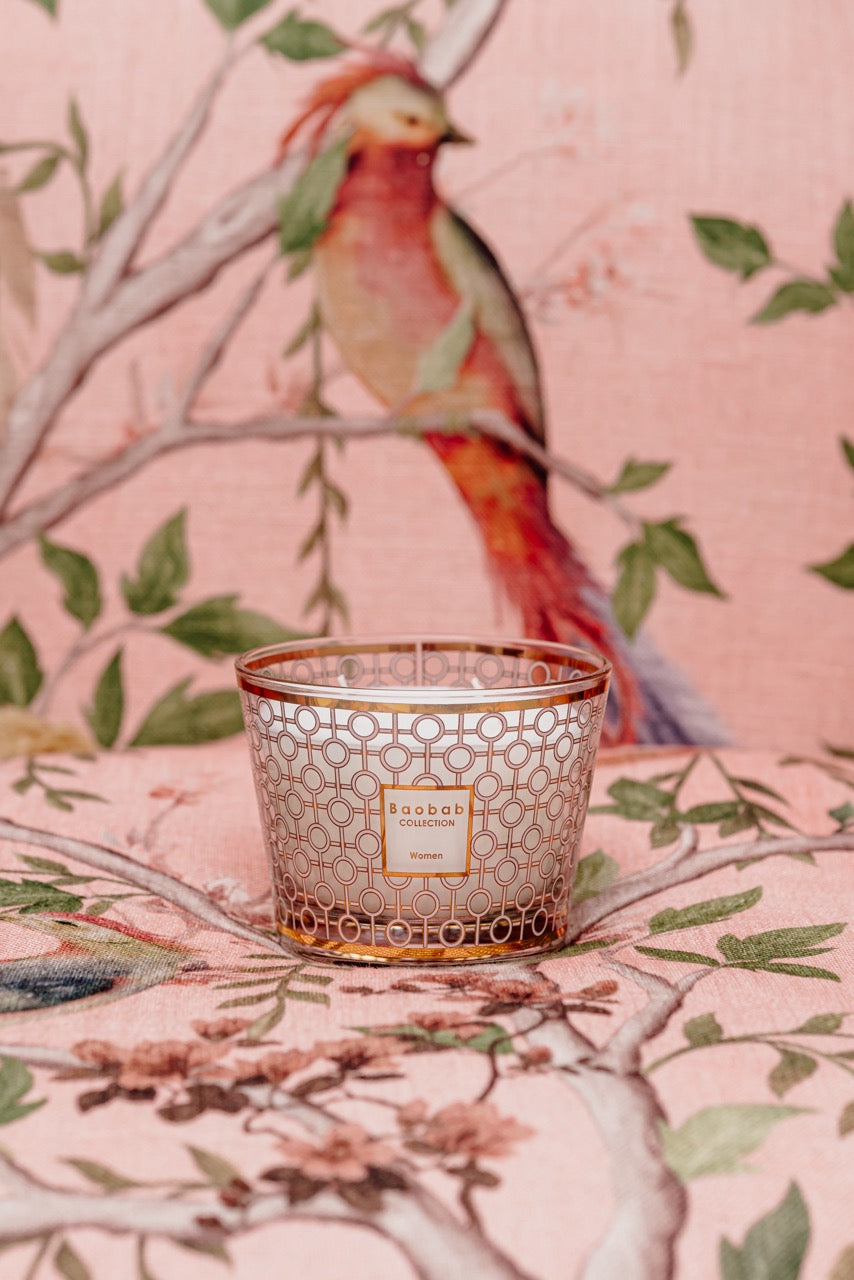 Front view of Baobab Max 10 Women candle in pink glass with gold geometric pattern and label reading Women on pink floral background