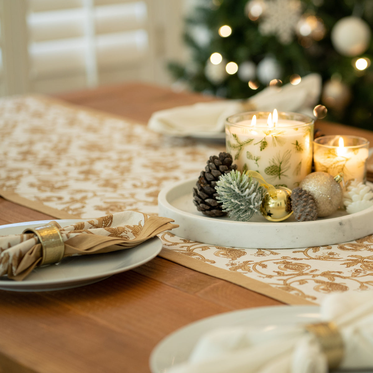 Mustard patterned napkins arranged on a table setting with plates, candles, and a floral centerpiece