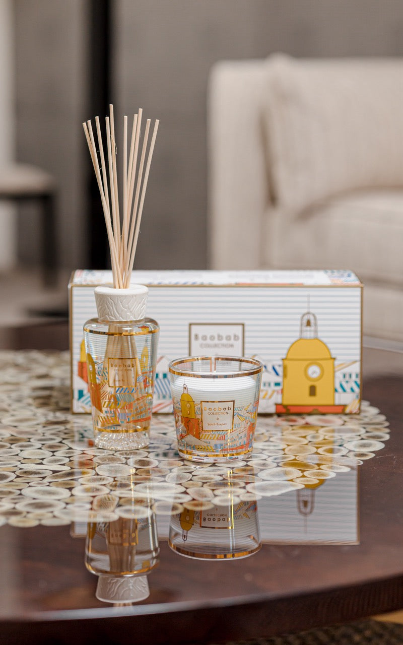Front view of My First Baobab Saint-Tropez diffuser and candle in gold-trimmed glass with matching gift box on table