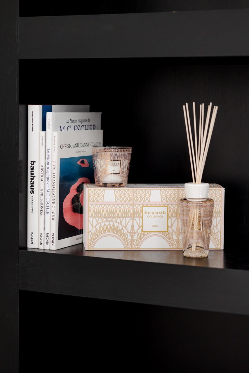 Front view of Baobab Collection Paris gift box with matching pink-and-gold glass candle and reed diffuser on a dark shelf