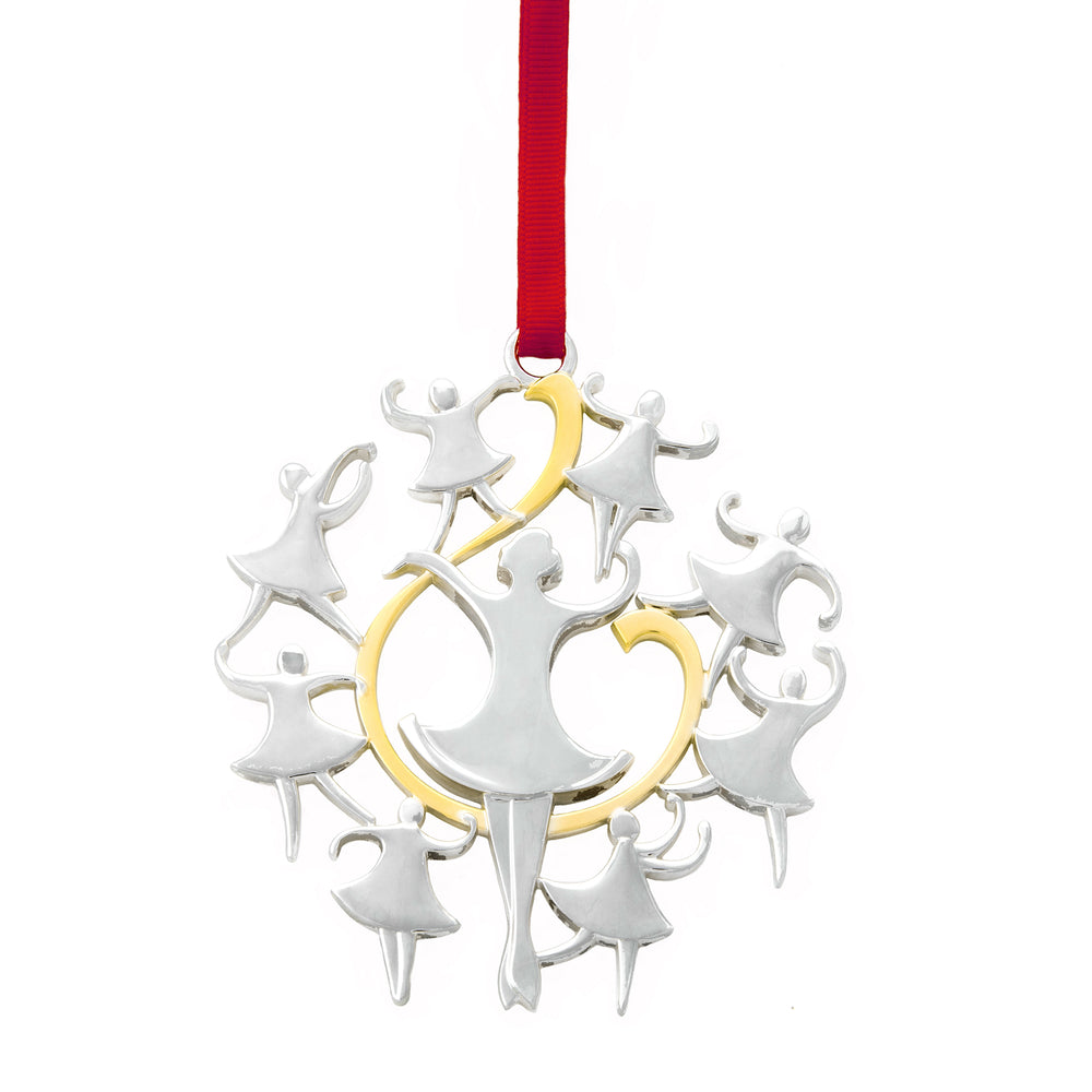 Front view of Nambe Nine Ladies Dancing ornament showing silver dancing figures with gold nine accent and red ribbon on white background