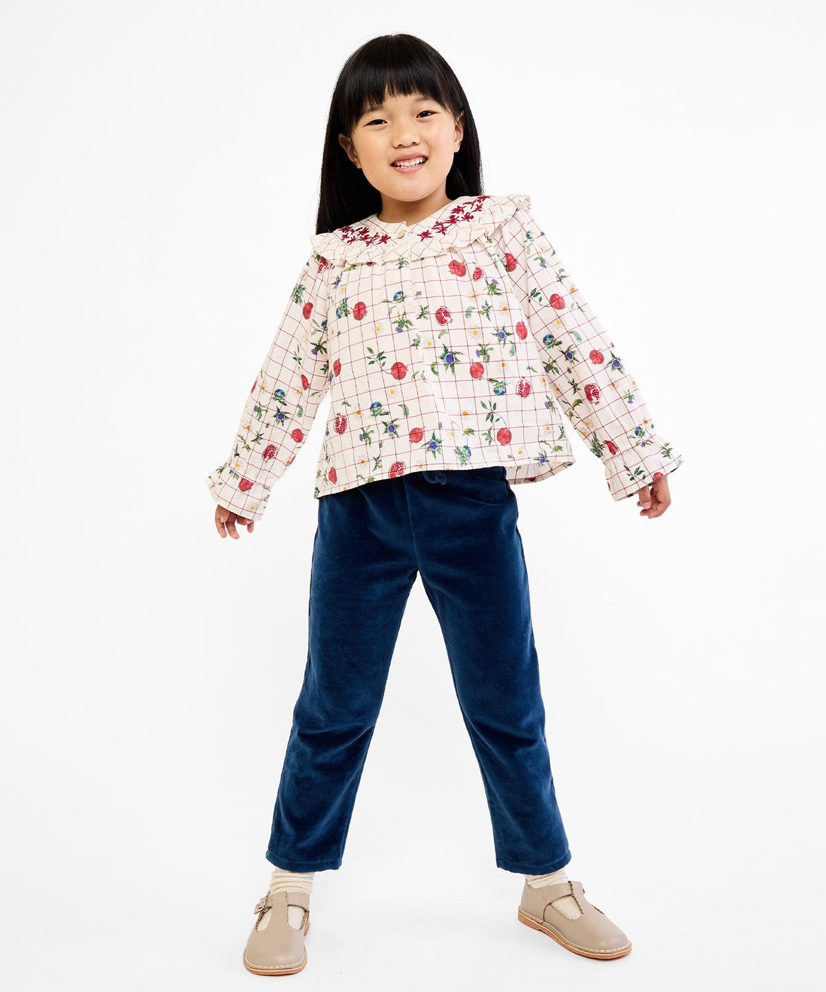 Front view of Maggie Blouse in Pomegranate Parade showcasing floral embroidered collar and ruffled cuffs on child against white