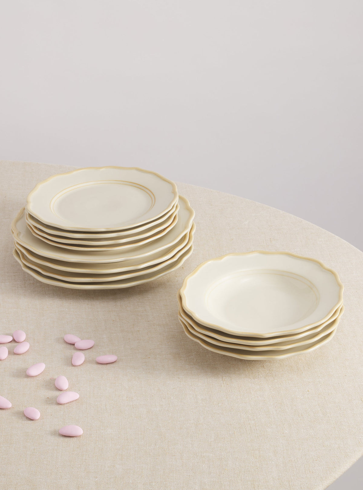 Overhead view of Colette Set with Pasta Bowl Set of 12 showcasing scalloped edges and gold rims on stacked plates over linen