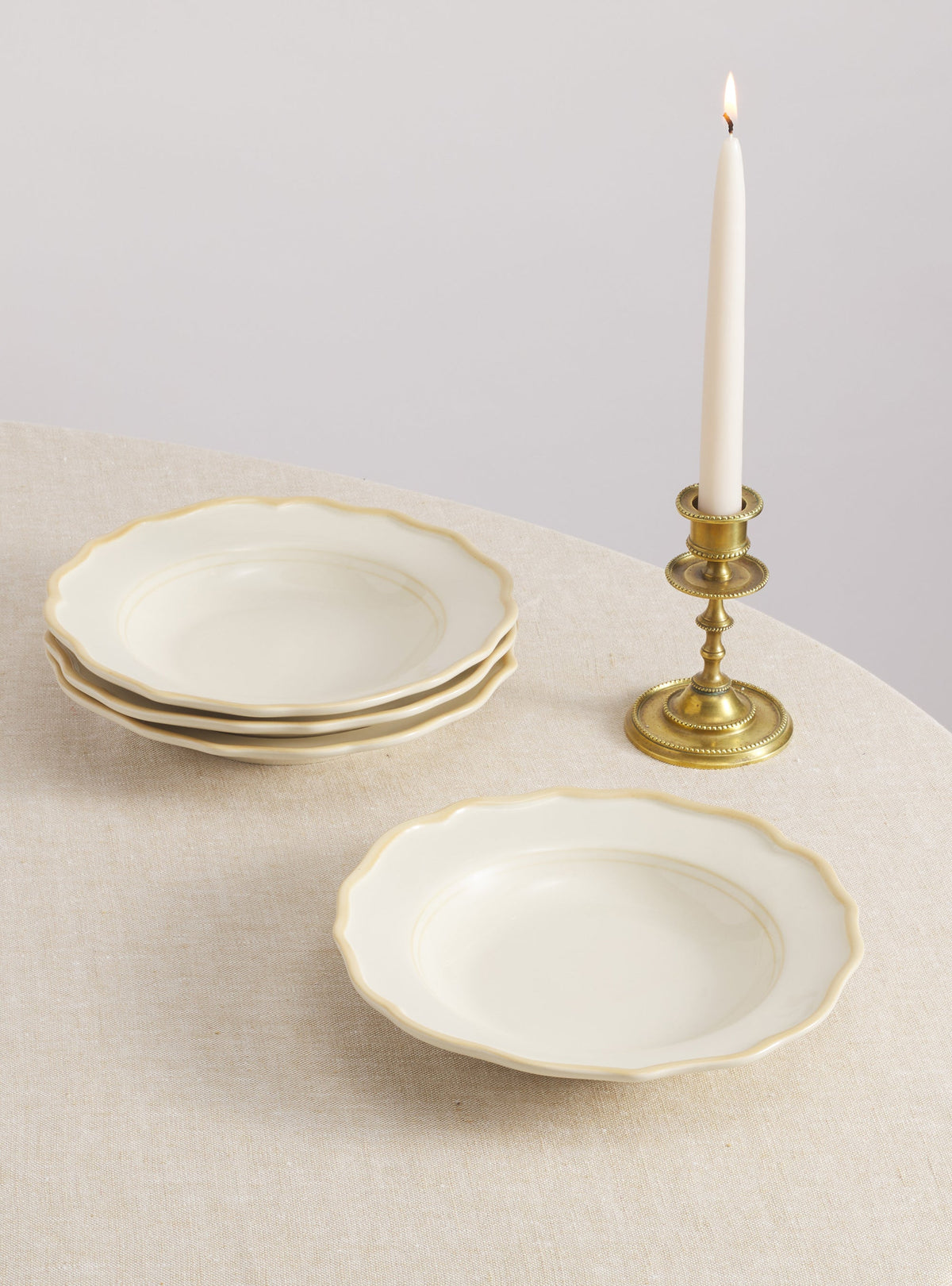 Overhead view of Colette Pasta Bowl, Set of 4 showcasing scalloped edges and hand-painted cream finish on a linen tablecloth