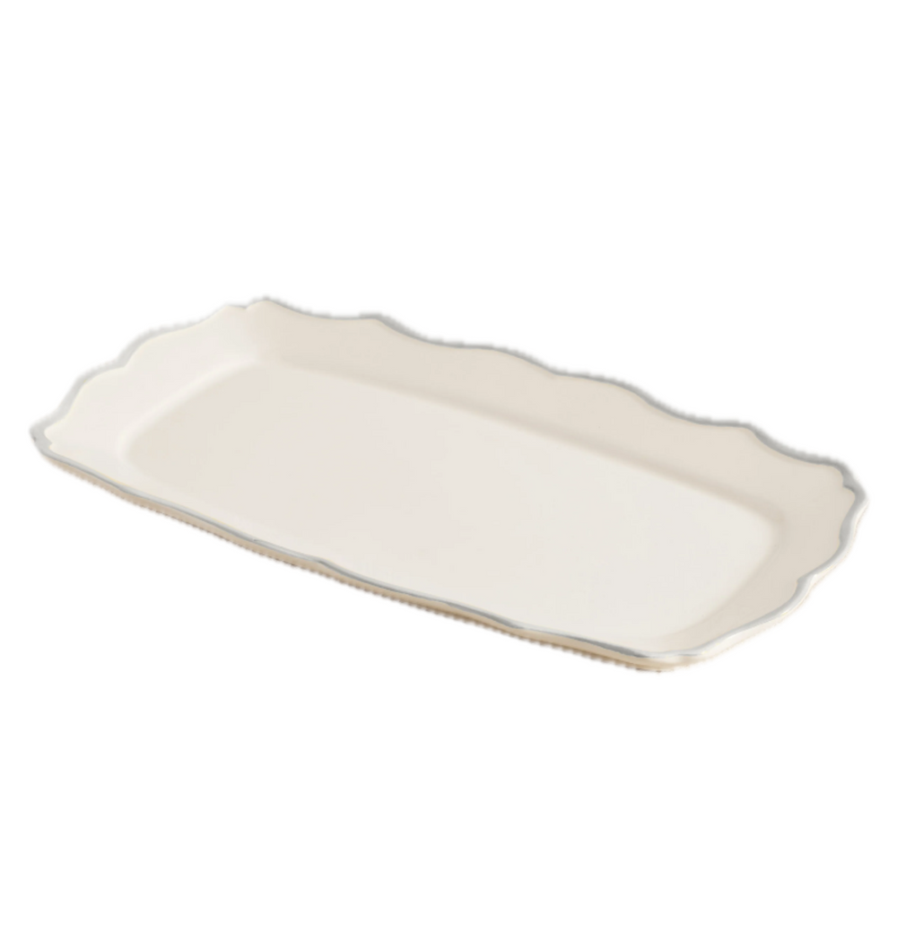 Angled view of Sylvia rectangular ceramic serving tray with cream glaze and scalloped rim on white background