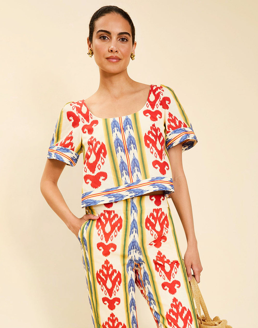 Woman wearing the Mestiza Maldives Top in Ikat Sunrise print, featuring a boxy silhouette, deep scoop neckline, pleated flutter sleeves, contrast ivory trim, and lightweight linen fabrication.