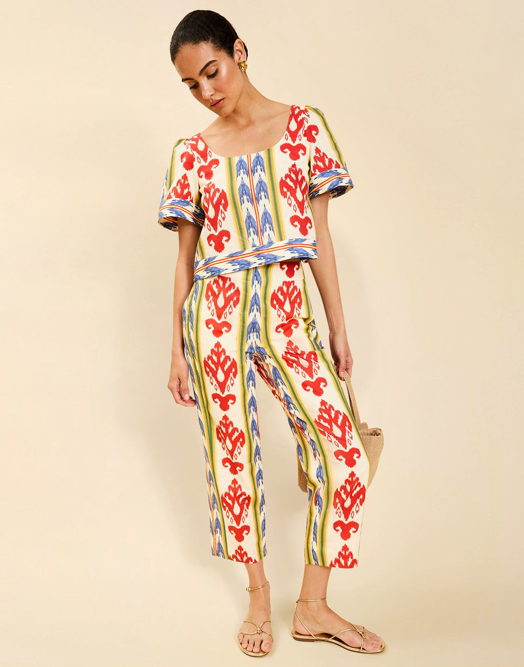 Woman wearing the Mestiza Palau Cigarette Pant in Ikat Sunrise print, featuring a slim-fit cigarette silhouette, front pleat detailing, cropped ankle-length fit, and lightweight linen fabrication.
