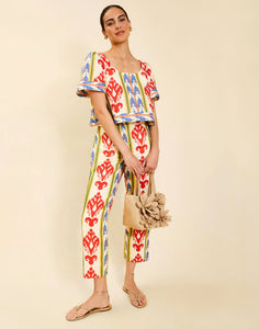 Woman wearing the Mestiza Maldives Top in Ikat Sunrise print, featuring a boxy silhouette, deep scoop neckline, pleated flutter sleeves, contrast ivory trim, and lightweight linen fabrication.