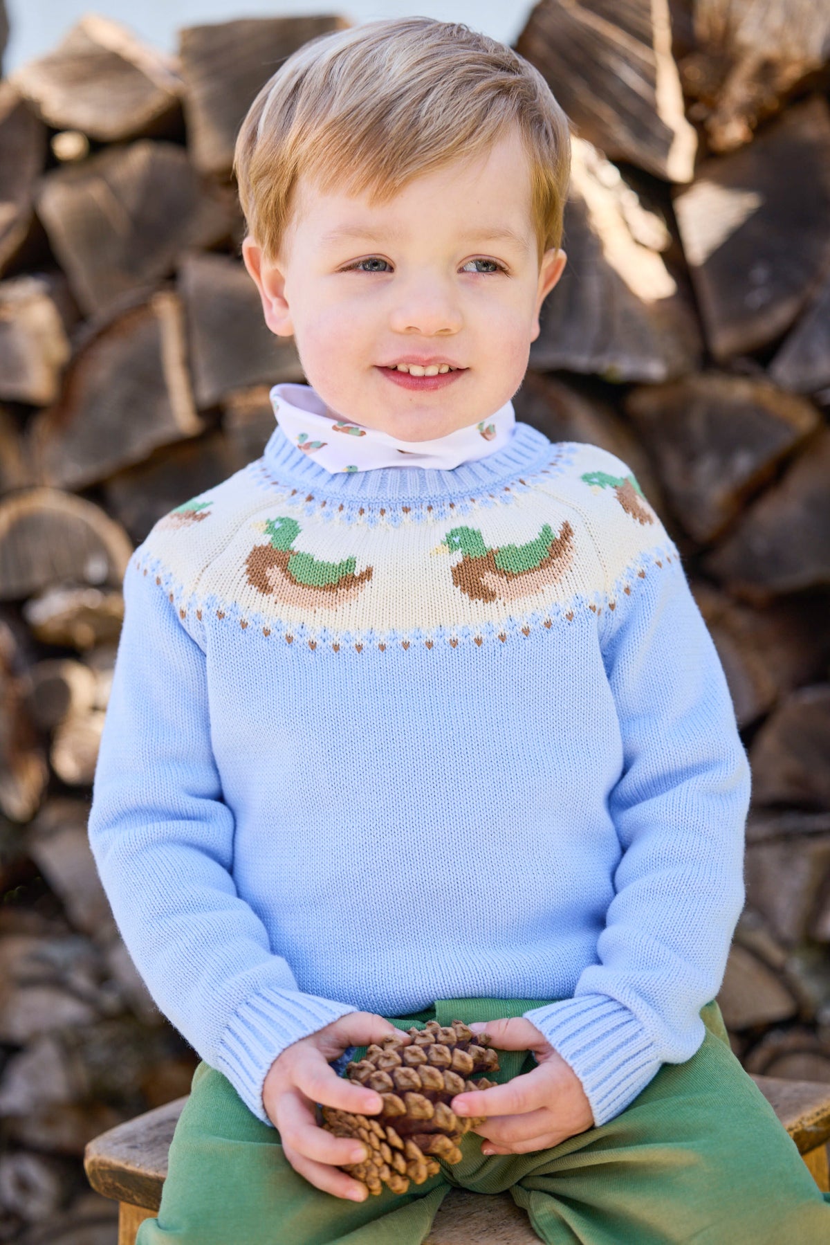 Front view of watercress corduroy banded pant on child model with light blue sweater featuring mallard yoke, wood pile